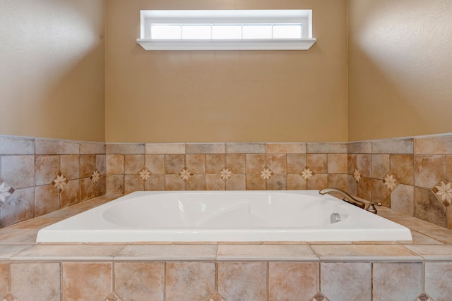 bathroom featuring a relaxing tiled tub and a wealth of natural light