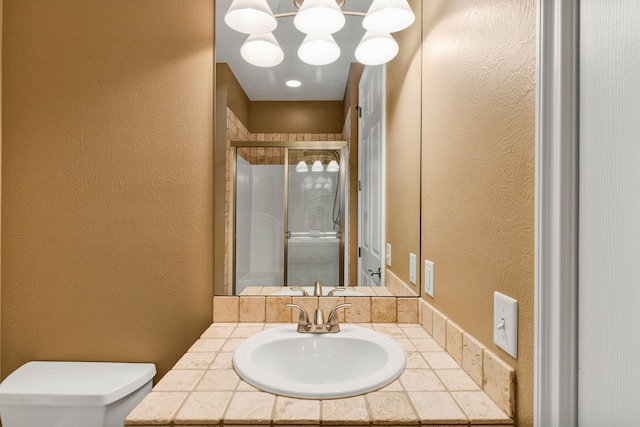 bathroom with a shower with shower door, sink, and toilet