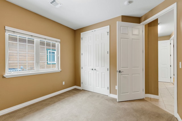 unfurnished bedroom featuring light carpet and a closet