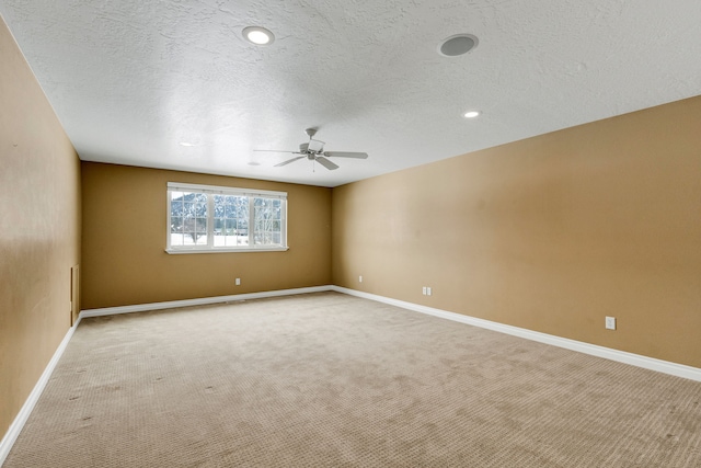 carpeted empty room with ceiling fan and a textured ceiling