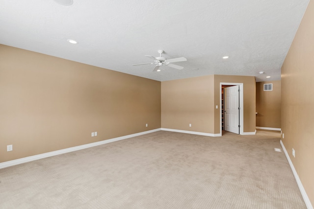 spare room featuring ceiling fan, light carpet, and a textured ceiling