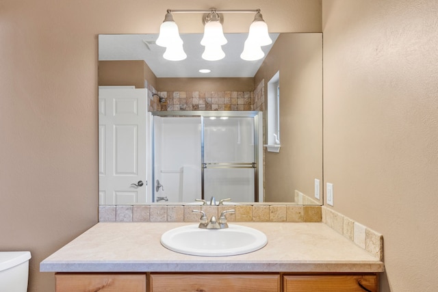 bathroom featuring a shower with door, vanity, and toilet