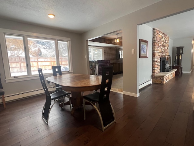 dining area featuring a baseboard heating unit, a fireplace, dark hardwood / wood-style floors, and a textured ceiling