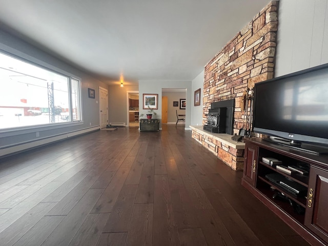 unfurnished living room with dark wood-type flooring, a stone fireplace, and a baseboard heating unit