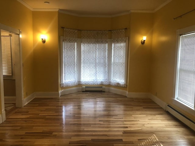 unfurnished room featuring baseboard heating, wood finished floors, and baseboards