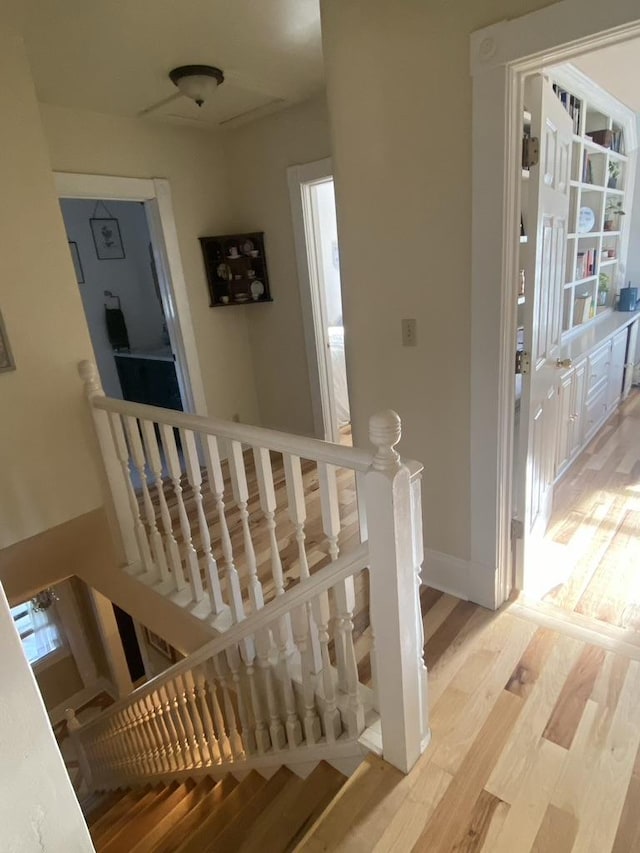 corridor featuring light wood-style floors, baseboards, and an upstairs landing