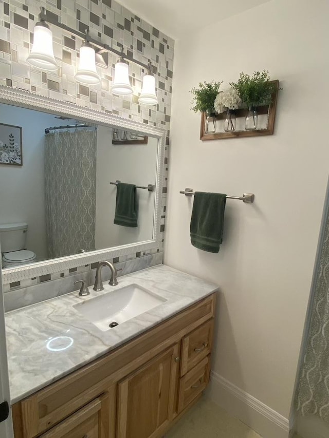 bathroom featuring vanity, toilet, and baseboards