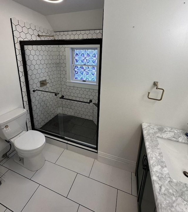 bathroom featuring toilet, a stall shower, vanity, baseboards, and tile patterned floors