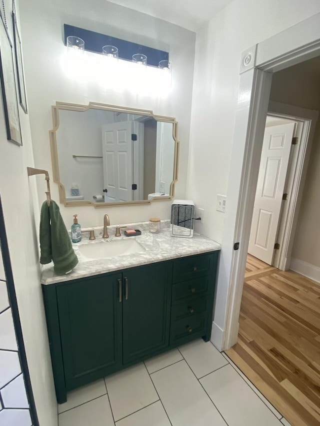 bathroom with wood finished floors, vanity, and baseboards