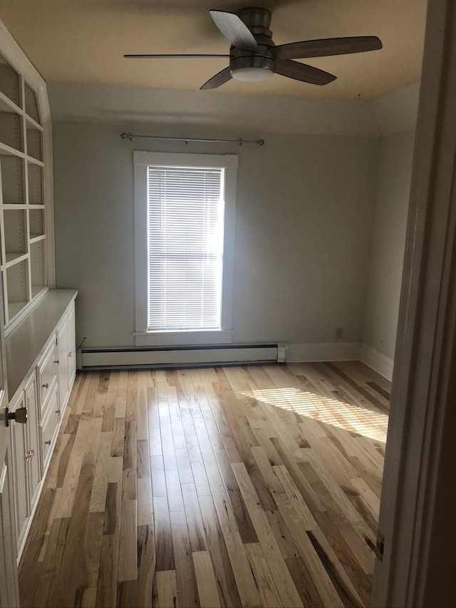 spare room with ceiling fan, a baseboard radiator, baseboards, and light wood-style floors