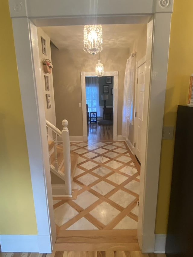 hall with stairway, baseboards, and a chandelier