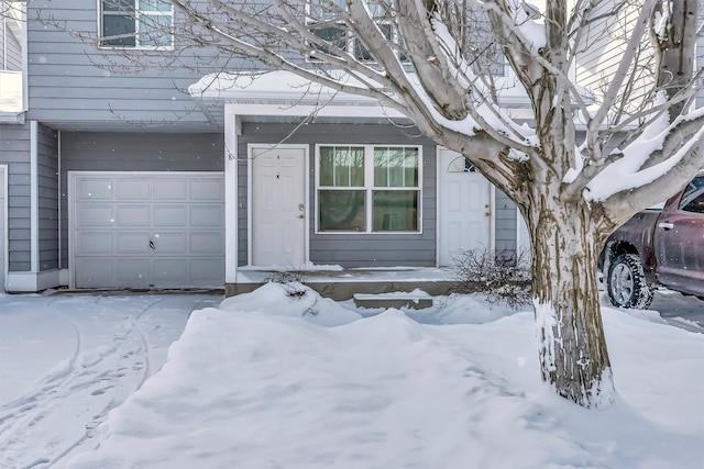 snow covered property entrance featuring a garage