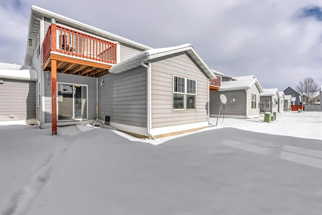 snow covered back of property featuring a balcony