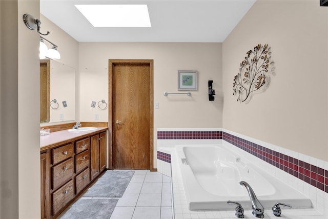 bathroom featuring tile patterned flooring, tiled tub, vanity, and a skylight