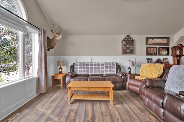 living room with hardwood / wood-style flooring, lofted ceiling, and a healthy amount of sunlight