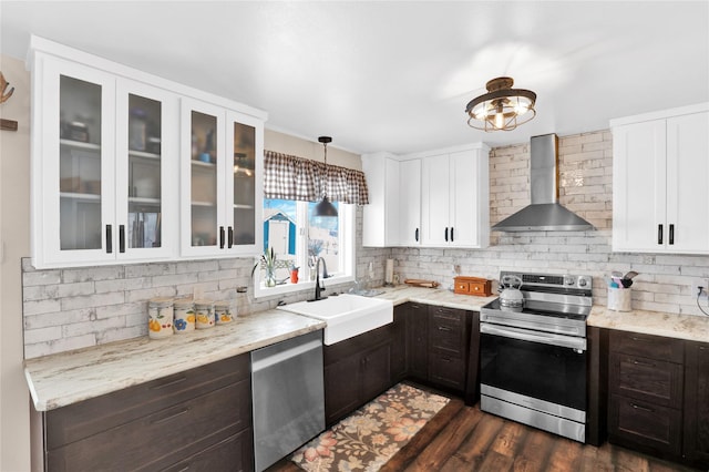 kitchen featuring hanging light fixtures, backsplash, stainless steel appliances, white cabinets, and wall chimney exhaust hood