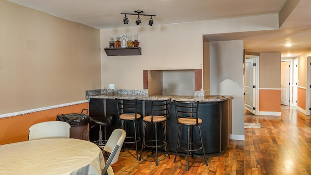 bar featuring dark hardwood / wood-style flooring and light stone counters