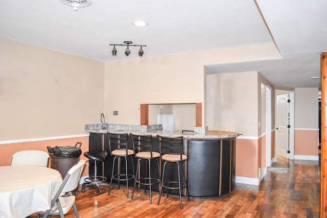 35011 Little Marten Rd, Ronan, MT 59864 - kitchen with a breakfast bar, wood finished floors, baseboards, a peninsula, and light stone countertops