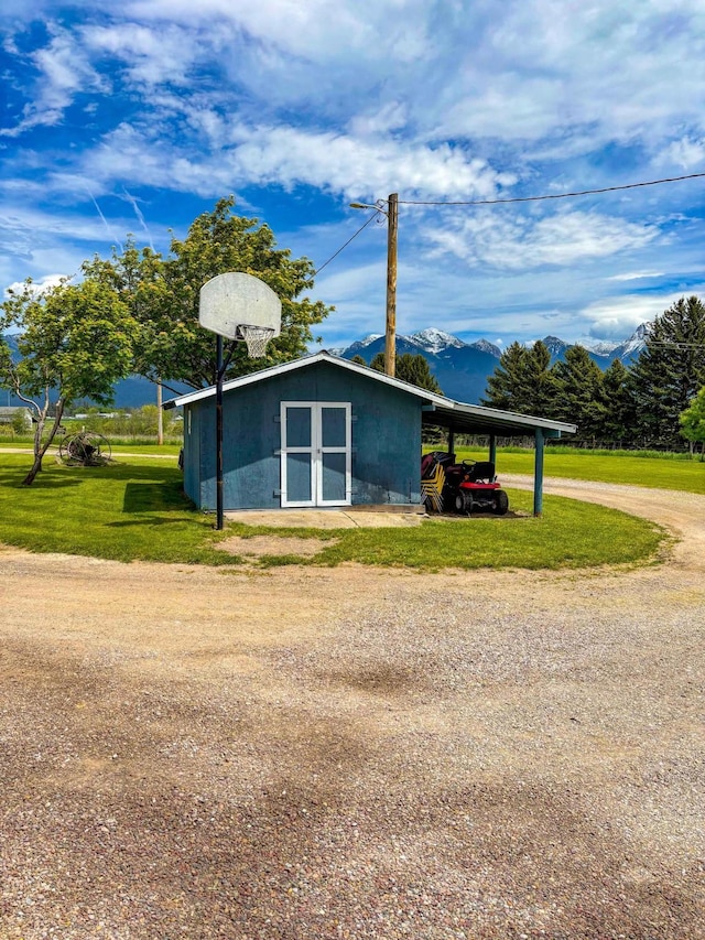 view of home's exterior with a carport, a mountain view, a lawn, and a shed