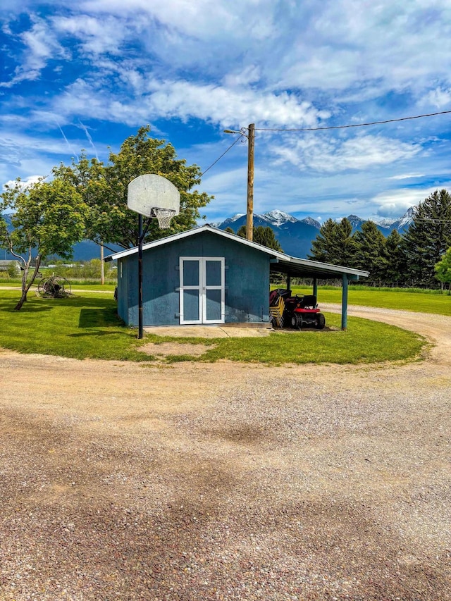 35011 Little Marten Rd, Ronan, MT 59864 - view of home's exterior featuring a lawn, an outbuilding, a carport, dirt driveway, and a mountain view