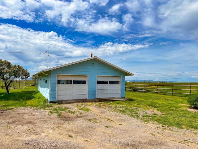 garage with a rural view and a lawn