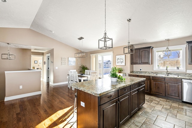 kitchen featuring pendant lighting, sink, dishwasher, a center island, and dark brown cabinetry