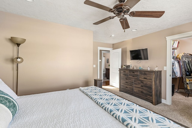 bedroom featuring ceiling fan, a textured ceiling, a spacious closet, light colored carpet, and a closet