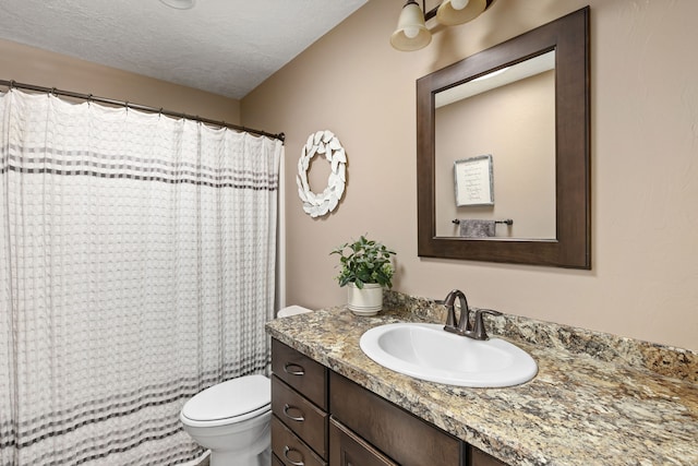 bathroom with vanity, toilet, and a textured ceiling