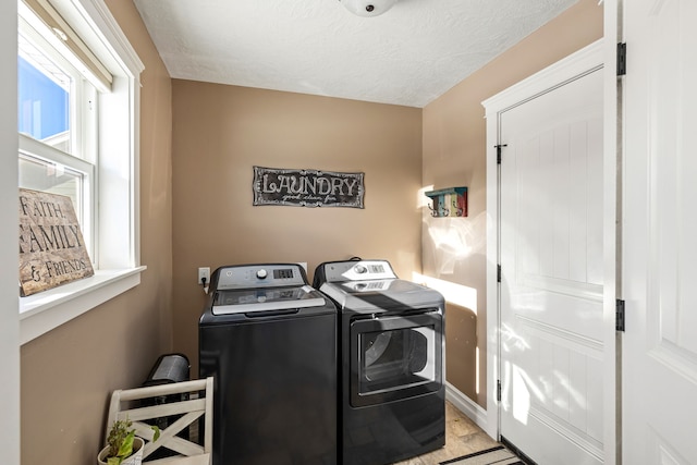 laundry area with washing machine and clothes dryer and a textured ceiling