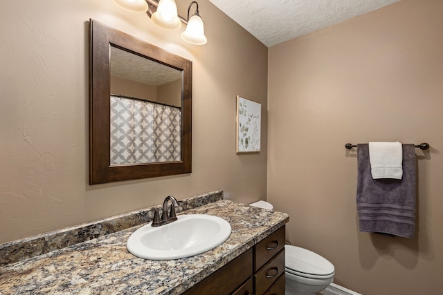 bathroom with vanity, a textured ceiling, and toilet