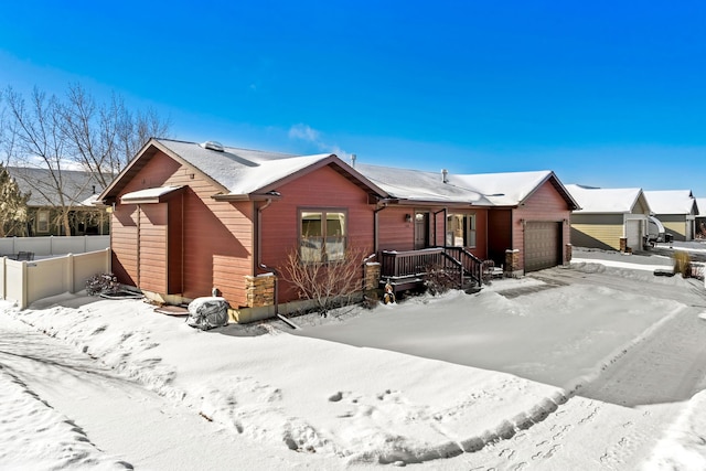 snow covered back of property with a garage