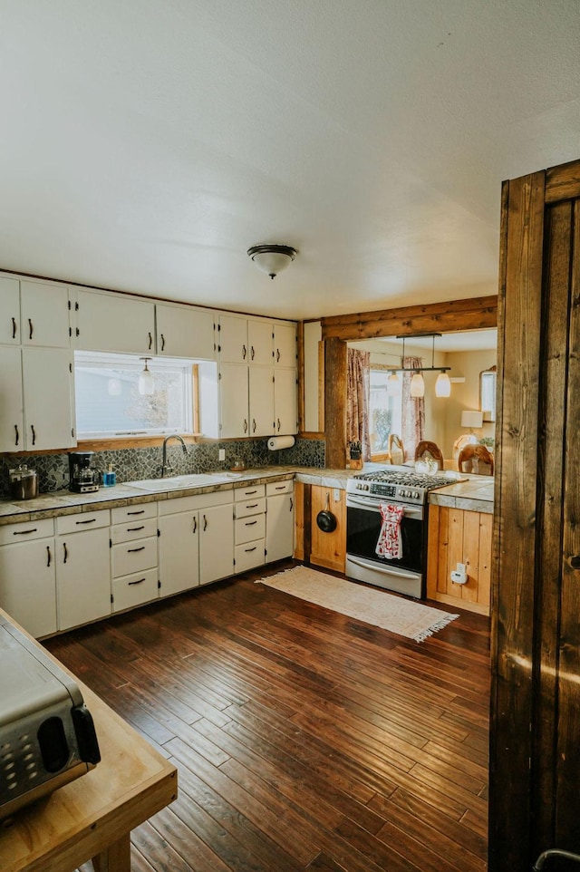 kitchen featuring dark wood-type flooring, sink, stainless steel gas range oven, backsplash, and white cabinets