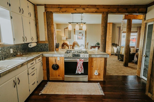 kitchen with dark wood-type flooring, hanging light fixtures, backsplash, stainless steel range with gas stovetop, and kitchen peninsula