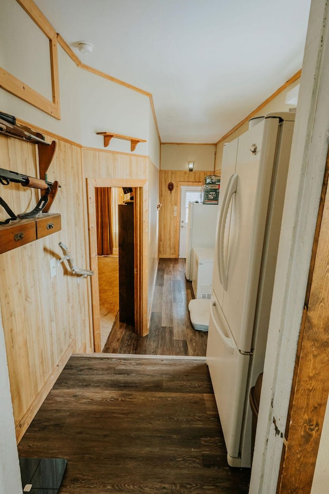 interior space featuring wood walls, light brown cabinets, white refrigerator, ornamental molding, and dark hardwood / wood-style flooring