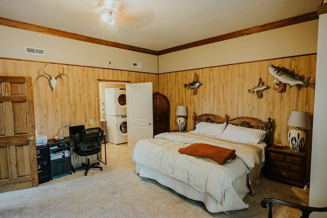 carpeted bedroom with crown molding, stacked washer and clothes dryer, and wood walls