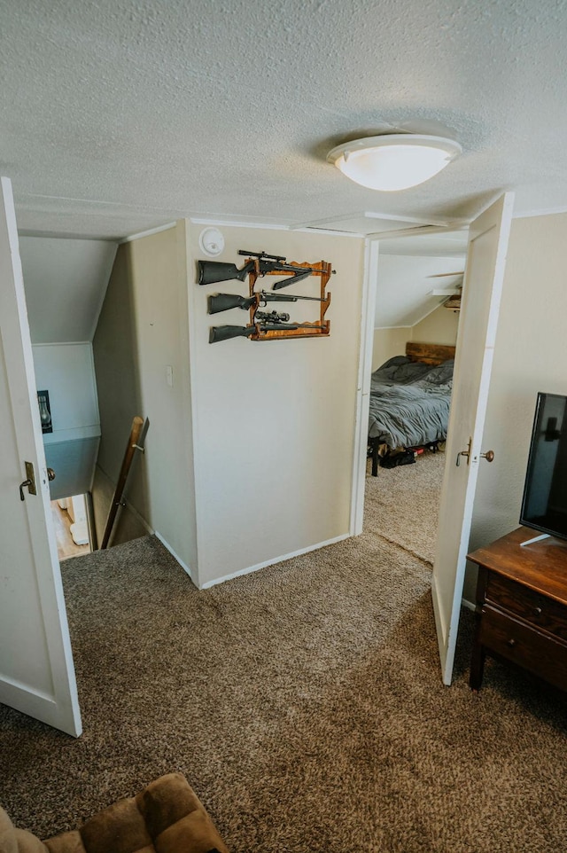 hall featuring vaulted ceiling, a textured ceiling, and carpet