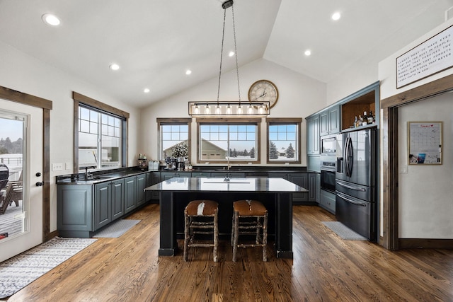 kitchen featuring a kitchen island, gray cabinetry, a kitchen breakfast bar, and appliances with stainless steel finishes