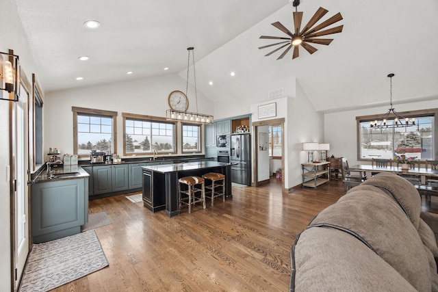 living room featuring dark wood-type flooring, sink, a notable chandelier, and high vaulted ceiling