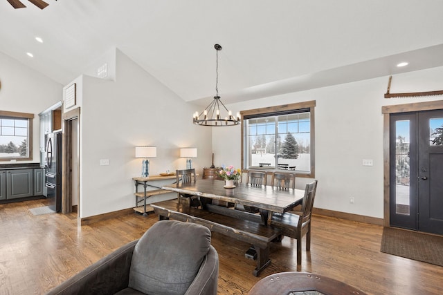 dining area with hardwood / wood-style flooring, high vaulted ceiling, and a chandelier