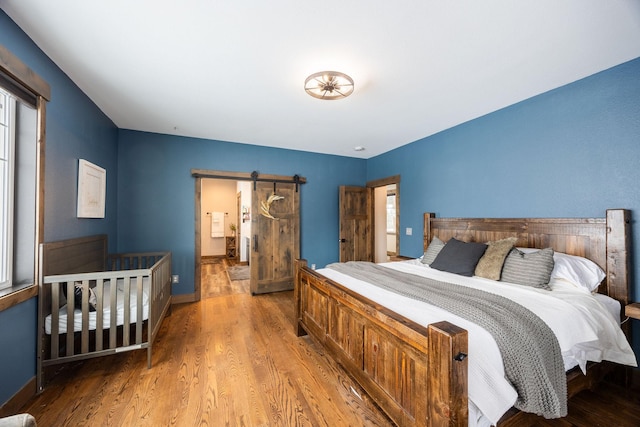 bedroom with hardwood / wood-style flooring and a barn door