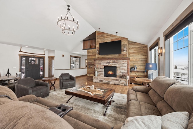 living room with a notable chandelier, high vaulted ceiling, a fireplace, and light hardwood / wood-style floors