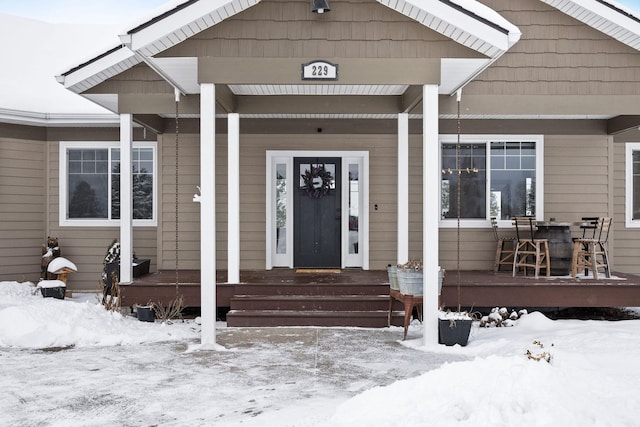 snow covered property entrance with covered porch