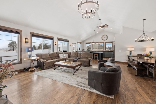 living room with hardwood / wood-style flooring, plenty of natural light, ceiling fan with notable chandelier, and high vaulted ceiling