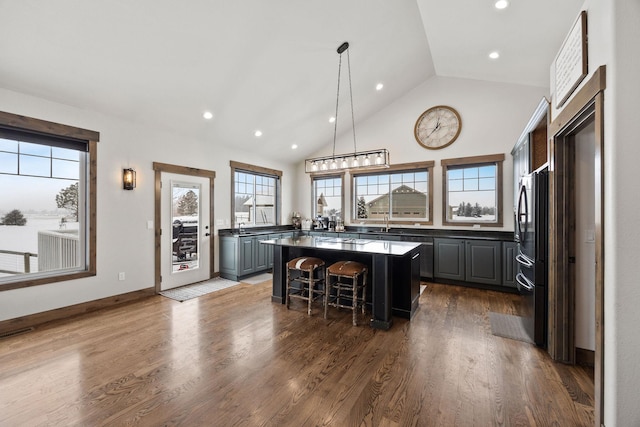 kitchen featuring dark wood-type flooring, gray cabinets, black refrigerator, a kitchen breakfast bar, and a kitchen island