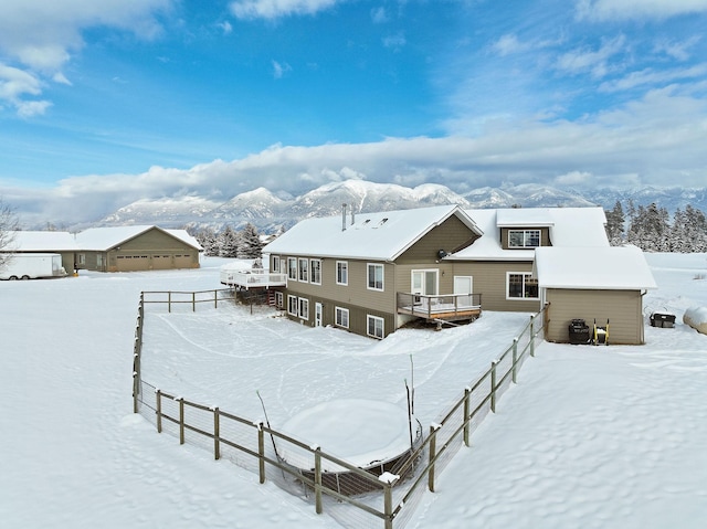 snow covered back of property featuring a deck with mountain view