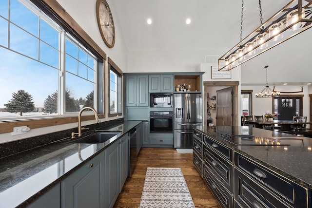 kitchen with sink, decorative light fixtures, black appliances, and dark stone counters