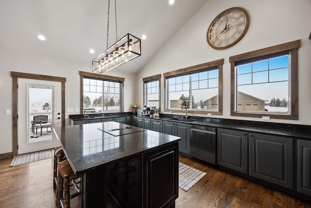 kitchen with sink, hanging light fixtures, dark stone countertops, dishwasher, and a kitchen island