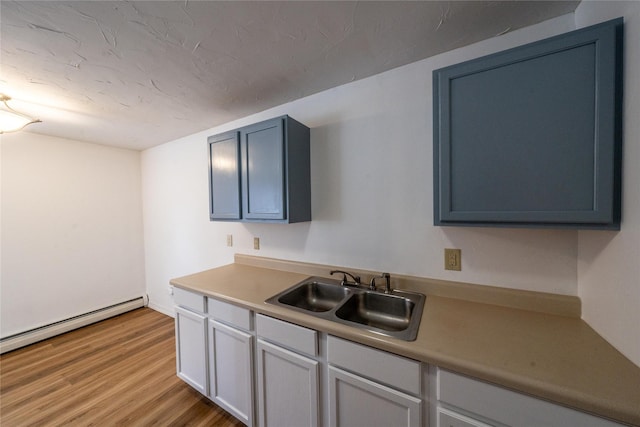 kitchen featuring blue cabinets, sink, a baseboard radiator, and light wood-type flooring