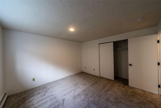 unfurnished bedroom with a baseboard heating unit, a closet, and carpet flooring