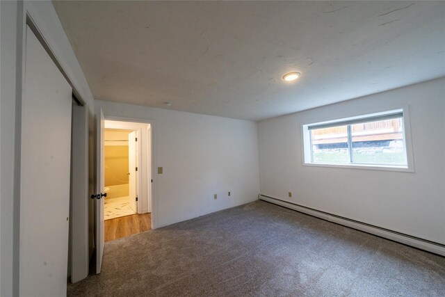 unfurnished bedroom featuring carpet floors and baseboard heating